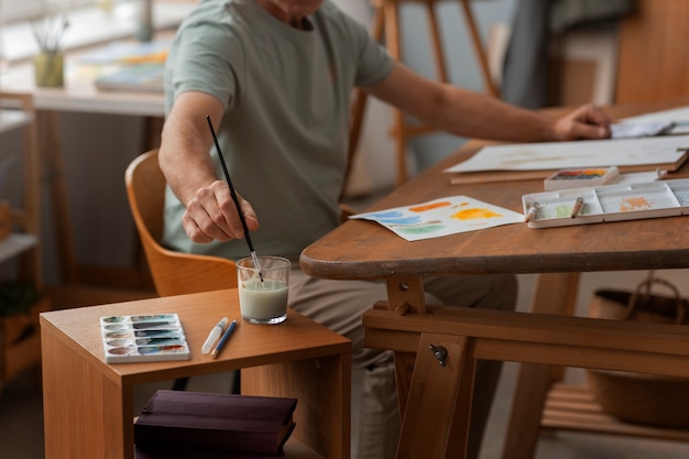 Foto grátis aquarelista sênior no estúdio trabalhando em sua arte