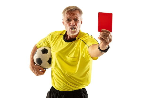 Árbitro segurando a bola e mostrando um cartão vermelho para um jogador de futebol ou futebol durante o jogo no fundo branco do estúdio.