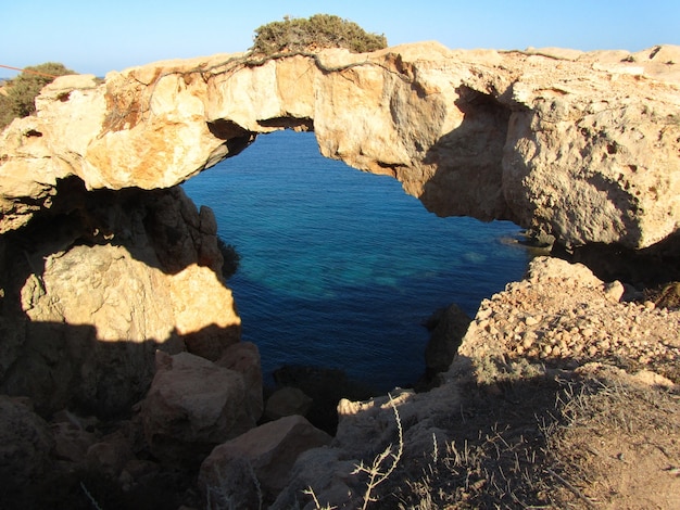 Arco de rocha natural cercado pelo mar no parque florestal nacional de cape greco, em chipre