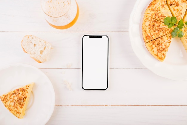 Área de trabalho de cozinha com torta e smartphone