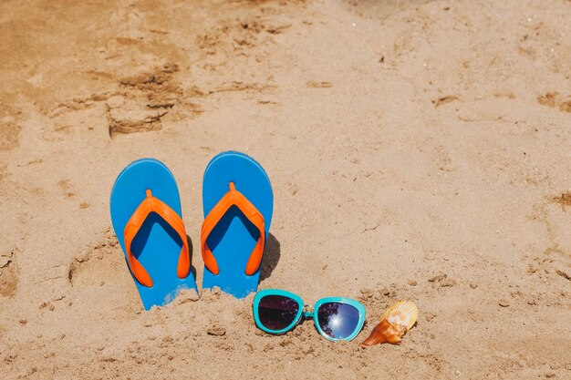 Areia com chinelas e conchas marinhas