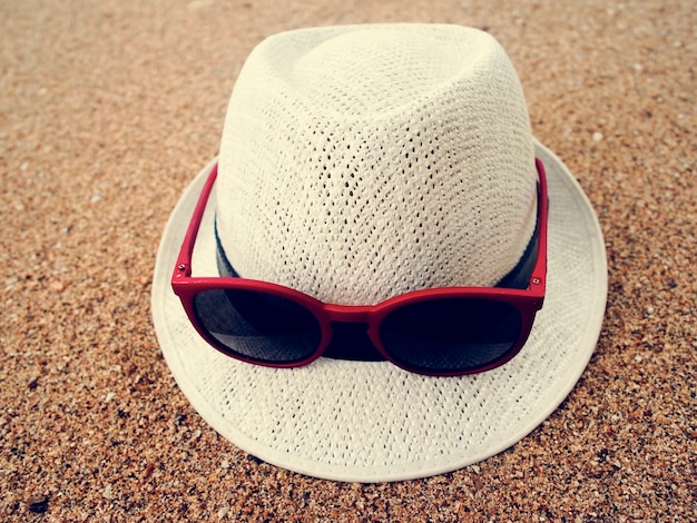 Areia da praia dos óculos de sol do chapéu relaxa férias
