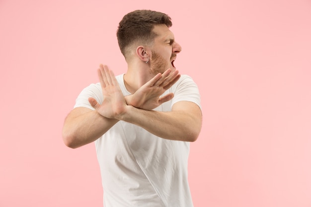 Argumente, discutindo o conceito. Belo retrato masculino com metade do comprimento isolado no estúdio rosa backgroud. Jovem emocional surpreso olhando para a câmera.