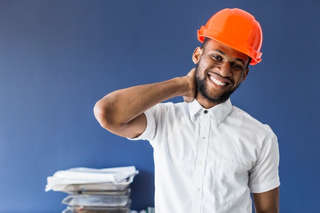 Foto grátis arquiteto masculino americano africano de pé contra a parede azul no local de trabalho