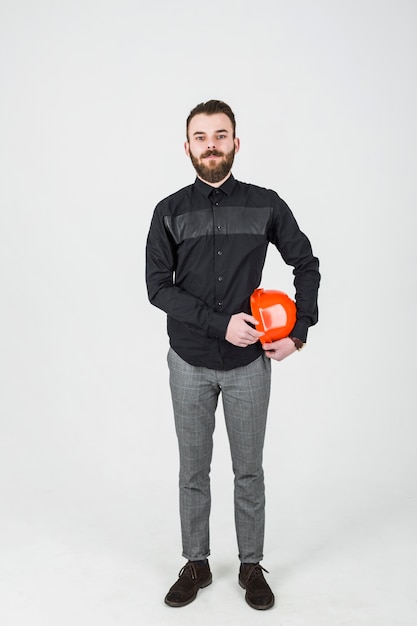 Arquiteto masculino confiante segurando um capacete de segurança laranja sobre fundo branco