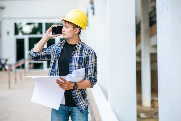 Arquitetos seguram plantas e falam ao telefone.