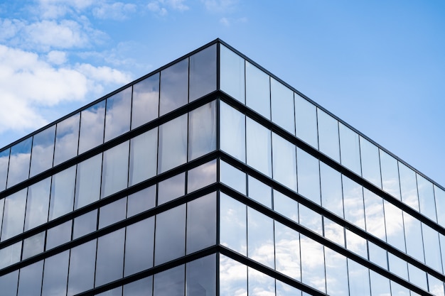 Arquitetura moderna de edifício de vidro com céu azul e nuvens