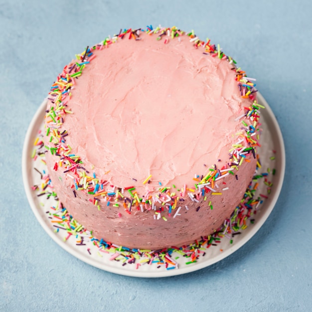 Arranjo de alto ângulo com bolo rosa e fundo azul