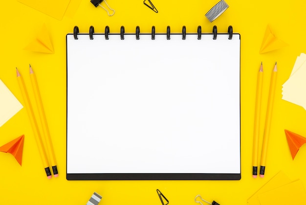 Foto grátis arranjo de artigos de papelaria vista superior sobre fundo amarelo com caderno vazio