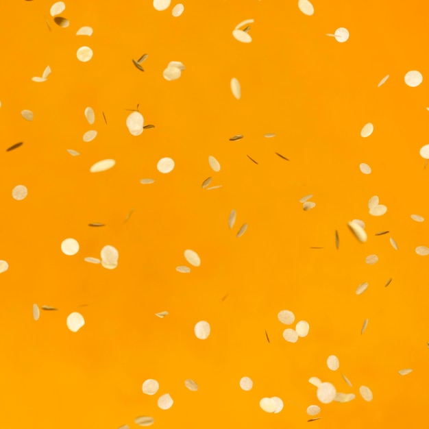 Arranjo de confetes dourados de festa na parede laranja