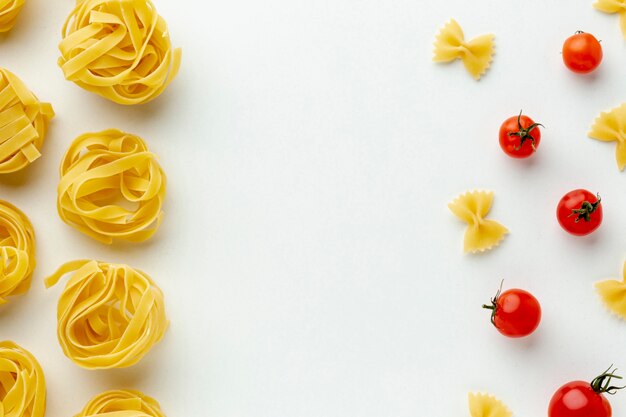 Arranjo de farfalle e tagliatelle não cozidos com tomates