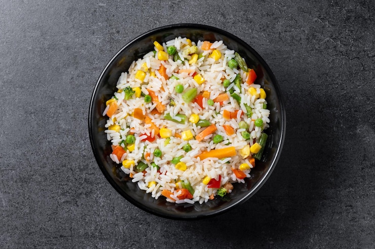 Foto grátis arroz branco com vegetais em uma tigela preta em uma mesa de madeira