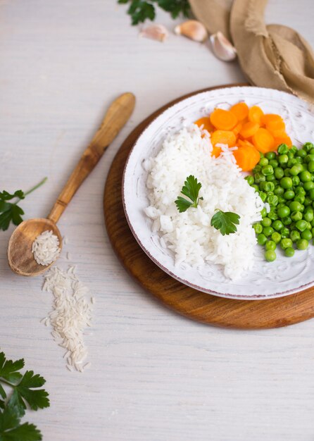 Arroz com legumes na tábua de madeira perto de colher