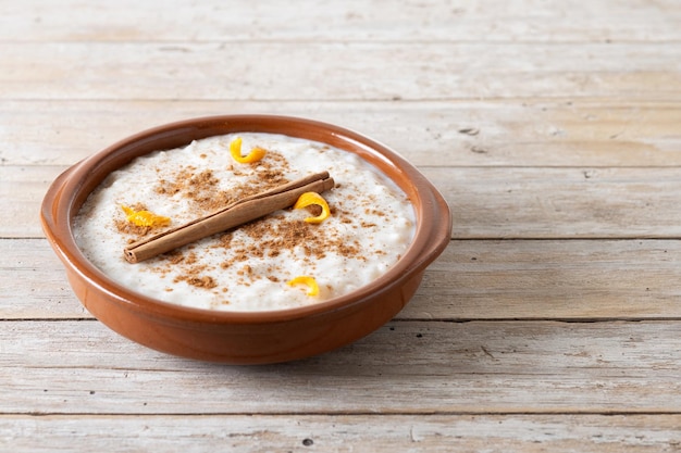 Arroz con leche Arroz doce com canela em tigela de barro na mesa de madeira