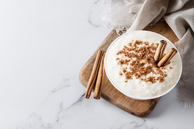 Foto grátis arroz con leche pudim de arroz com canela em uma tigela de barro em mármore branco vista superior