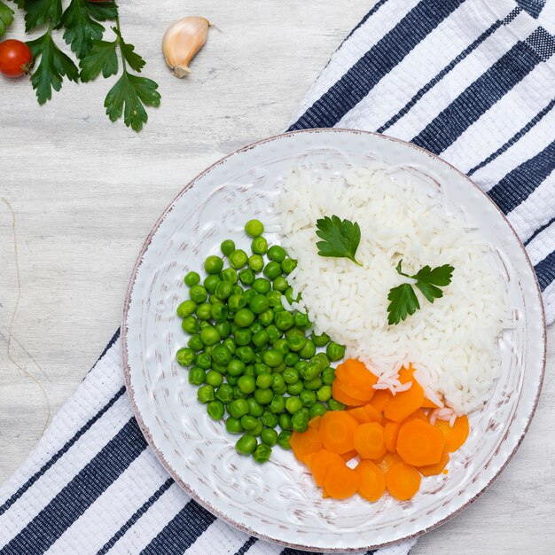 Arroz cozido com legumes e salsa no prato no guardanapo listrado