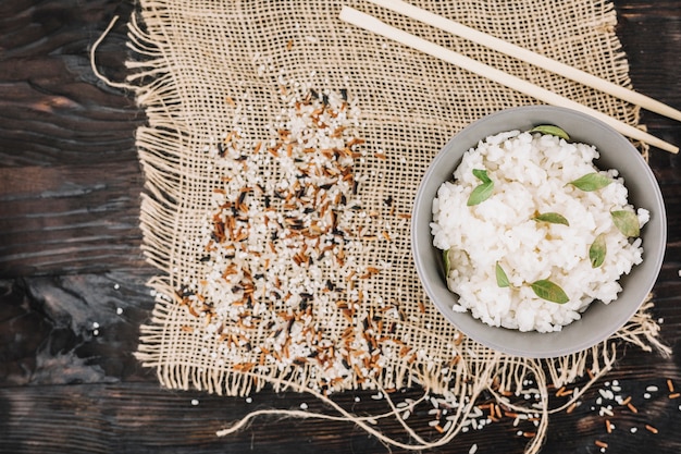 Foto grátis arroz cozido perto de pauzinhos e grãos derramados