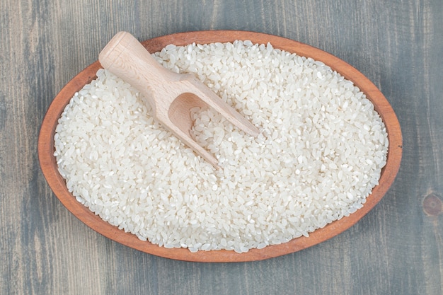 Arroz cru saudável com colher de pau em uma mesa de madeira