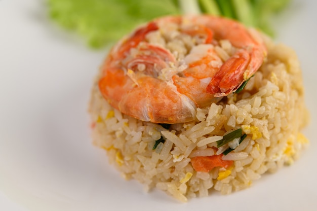 Arroz frito com camarão em um prato branco sobre uma mesa de madeira