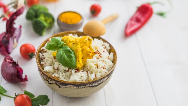 Arroz frito saudável com frango; cebola; tomate cereja e pimenta vermelha sobre a mesa branca