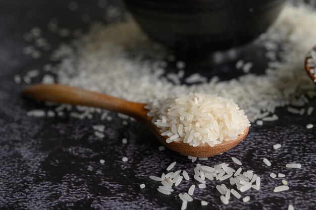 Arroz moído em uma tigela e uma colher de pau no chão de cimento preto.