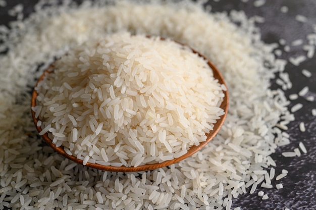 Arroz moído em uma tigela e uma colher de pau no chão de cimento preto.