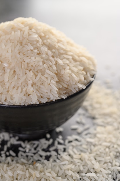 Arroz moído em uma tigela preta no chão de cimento preto.