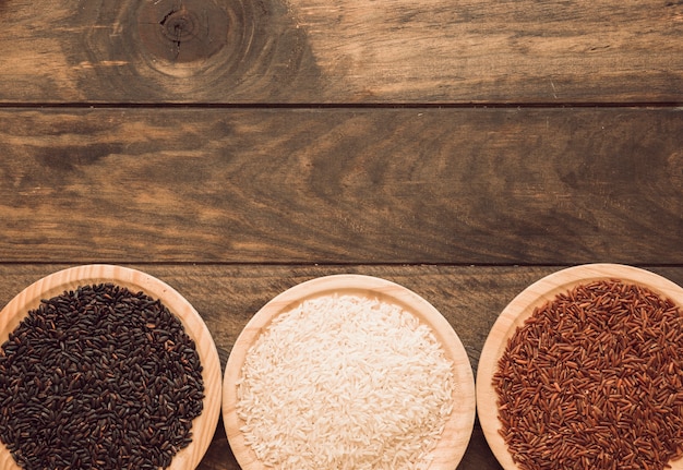 Foto grátis arroz preto vermelho; arroz branco e tigelas de grãos de arroz vermelho jasmim na mesa de madeira