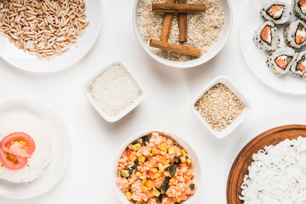 Arroz tufado; arroz frito chinês; arroz cru com paus de canela e sushi no fundo branco