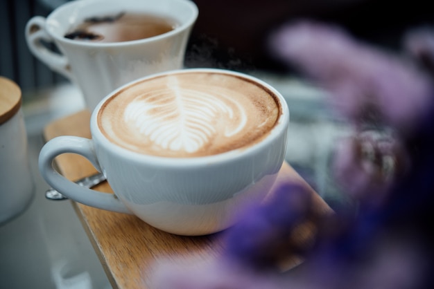 Arte latte quente na xícara de café na mesa de madeira na cafeteria