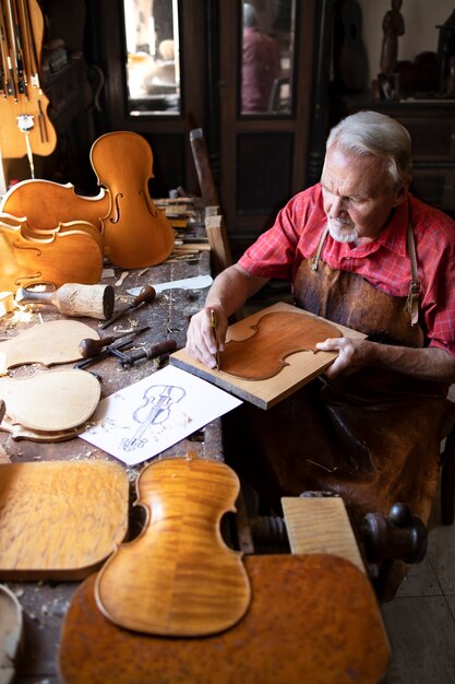 Artesão carpinteiro sênior fazendo violino em sua antiga oficina de carpinteiro