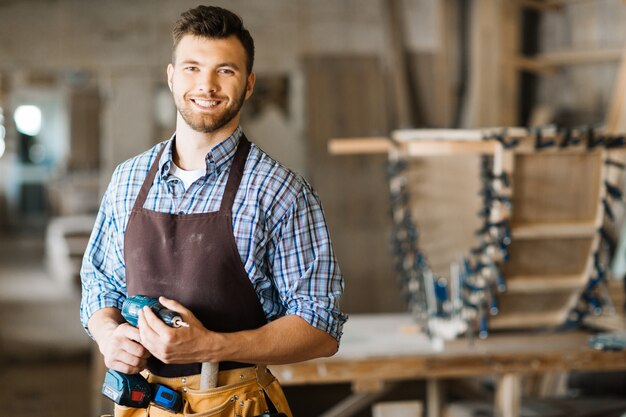 Artesão sorridente com furadeira elétrica