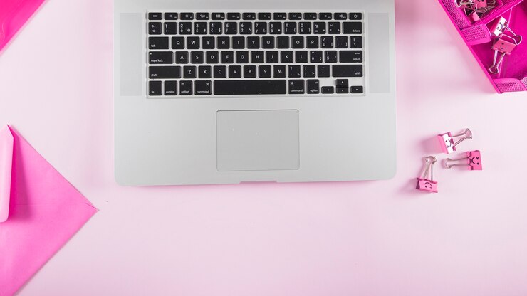 Foto grátis artigos de papelaria rosa perto do teclado do laptop