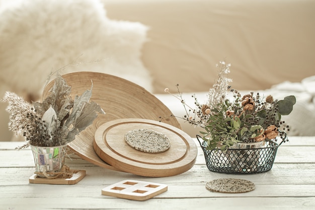 Artigos decorativos no interior aconchegante da sala, um vaso com flores secas na mesa de madeira clara.