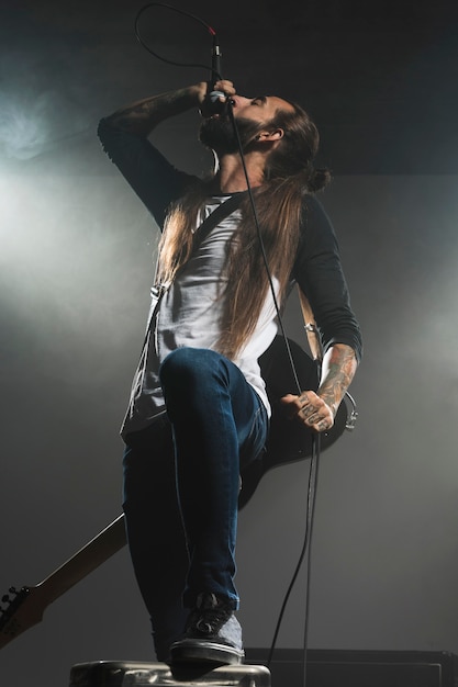 Artista cantando no palco e segurando um violão