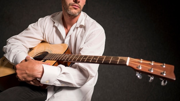 Foto grátis artista de camisa branca segurando seu violão