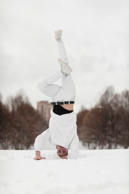 Foto grátis artista de hip-hop masculino em pé na cabeça enquanto na neve