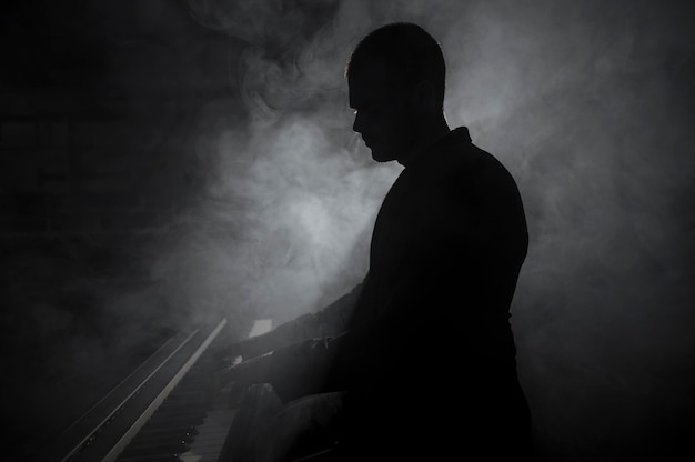 Artista de lado tocando fumaça de piano e efeitos de sombras