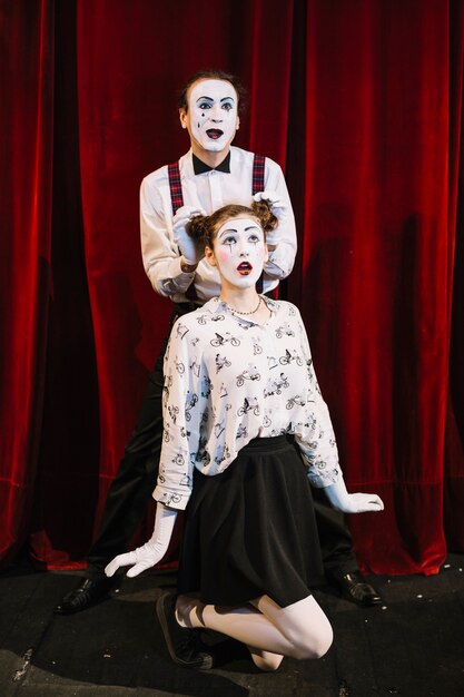 Artista de mímica masculina colocando a mão em pães de cabelo feminino mime