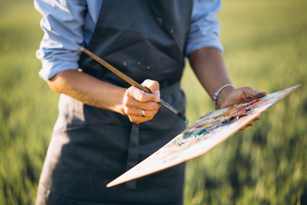 Artista de mulher, pintura com tintas a óleo em um campo