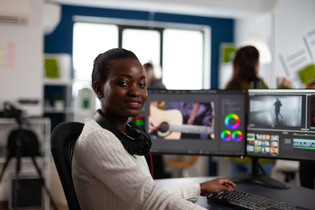 Artista editor de vídeo afro-americano olhando para a câmera sorrindo, editando projeto de vídeo de criatividade