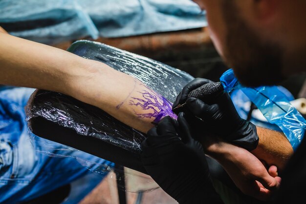 Artista fazendo tatuagem no braço