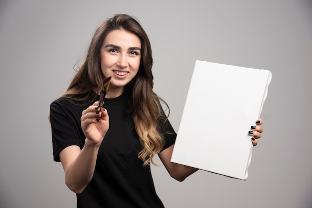 Artista feminina de camisa preta, segurando ferramentas artísticas.