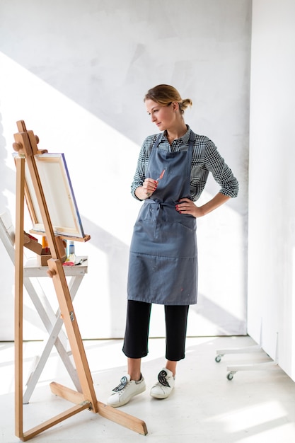 Foto grátis artista feminina olhando para pintura