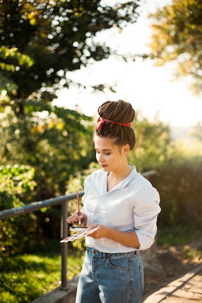 Foto grátis artista feminina pintando ao ar livre