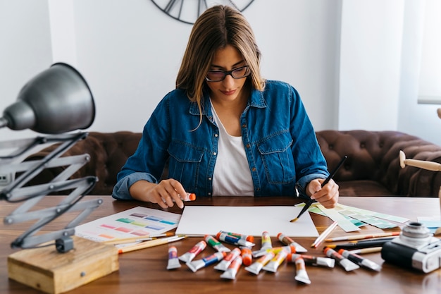 Artista feminino sentado na mesa de mesa