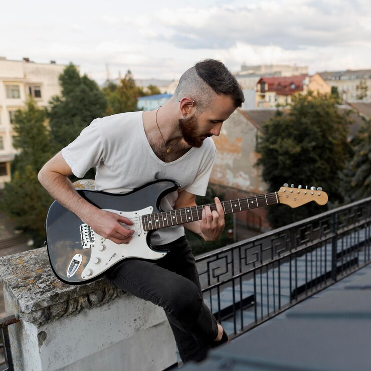 Foto grátis artista masculino no telhado tocando guitarra elétrica