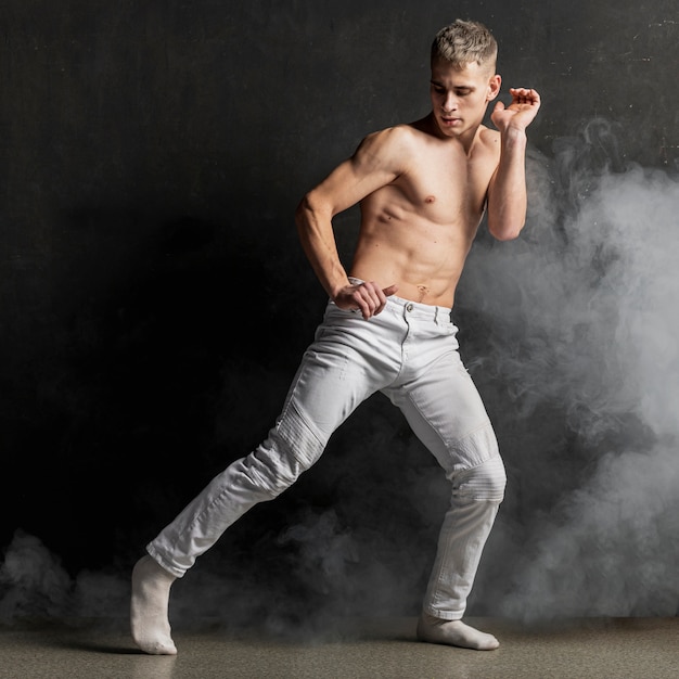 Artista masculino posando de jeans com meias e fumaça