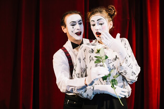 Artista mime masculino dando rosa branca para mime feminino surpreso