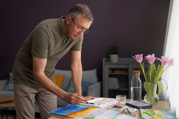 Foto grátis artista sênior no estúdio pintando com aquarela